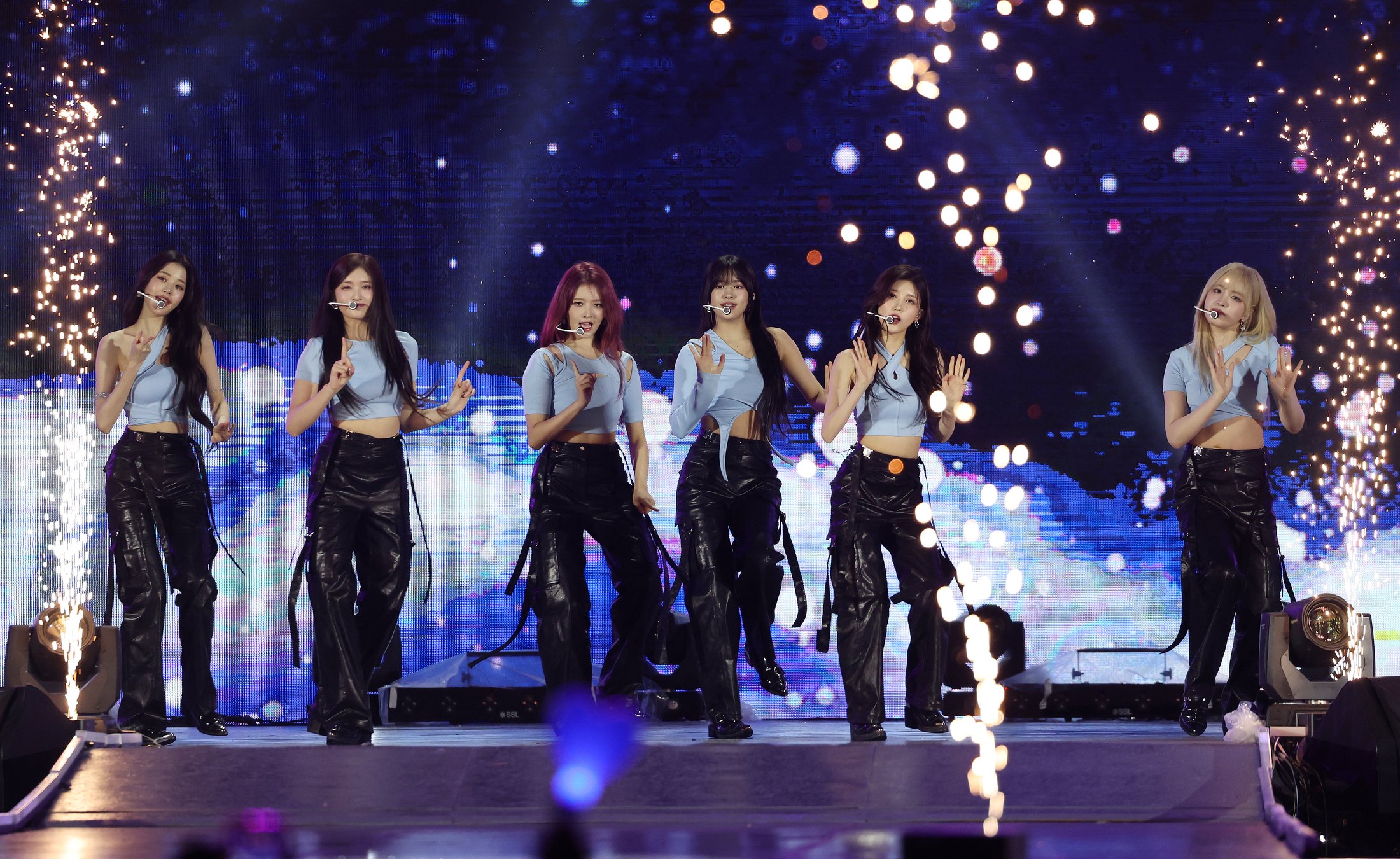 A K-pop group performing on stage under stage lighting